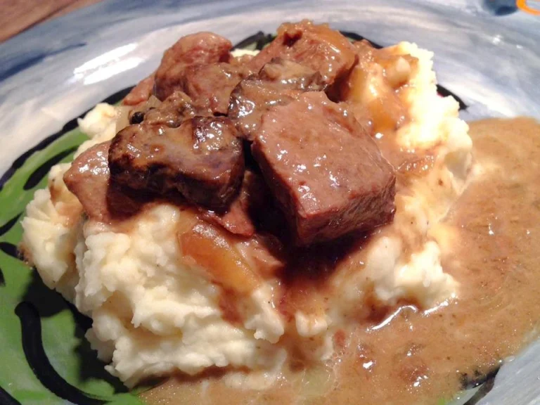 Crockpot beef tips and gravy served over mashed potatoes