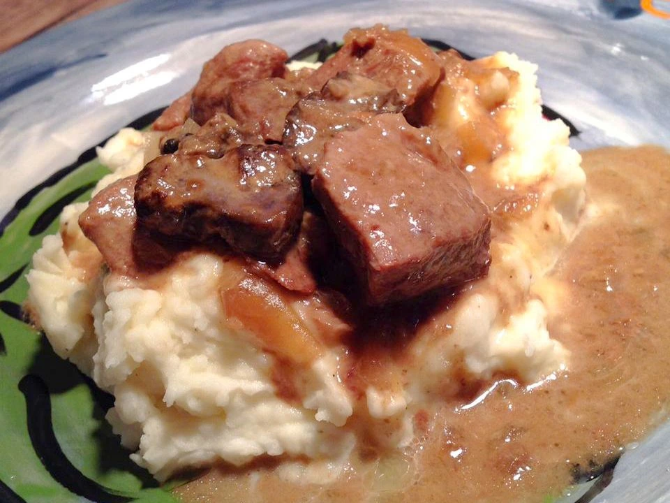 Crockpot beef tips and gravy served over mashed potatoes