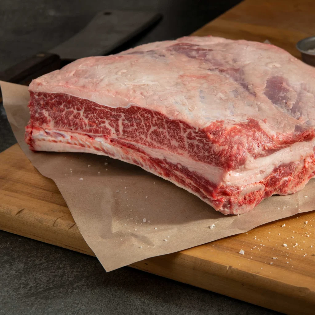 Raw bone-in beef short ribs on a butcher board showing rich marbling and thick meat cut