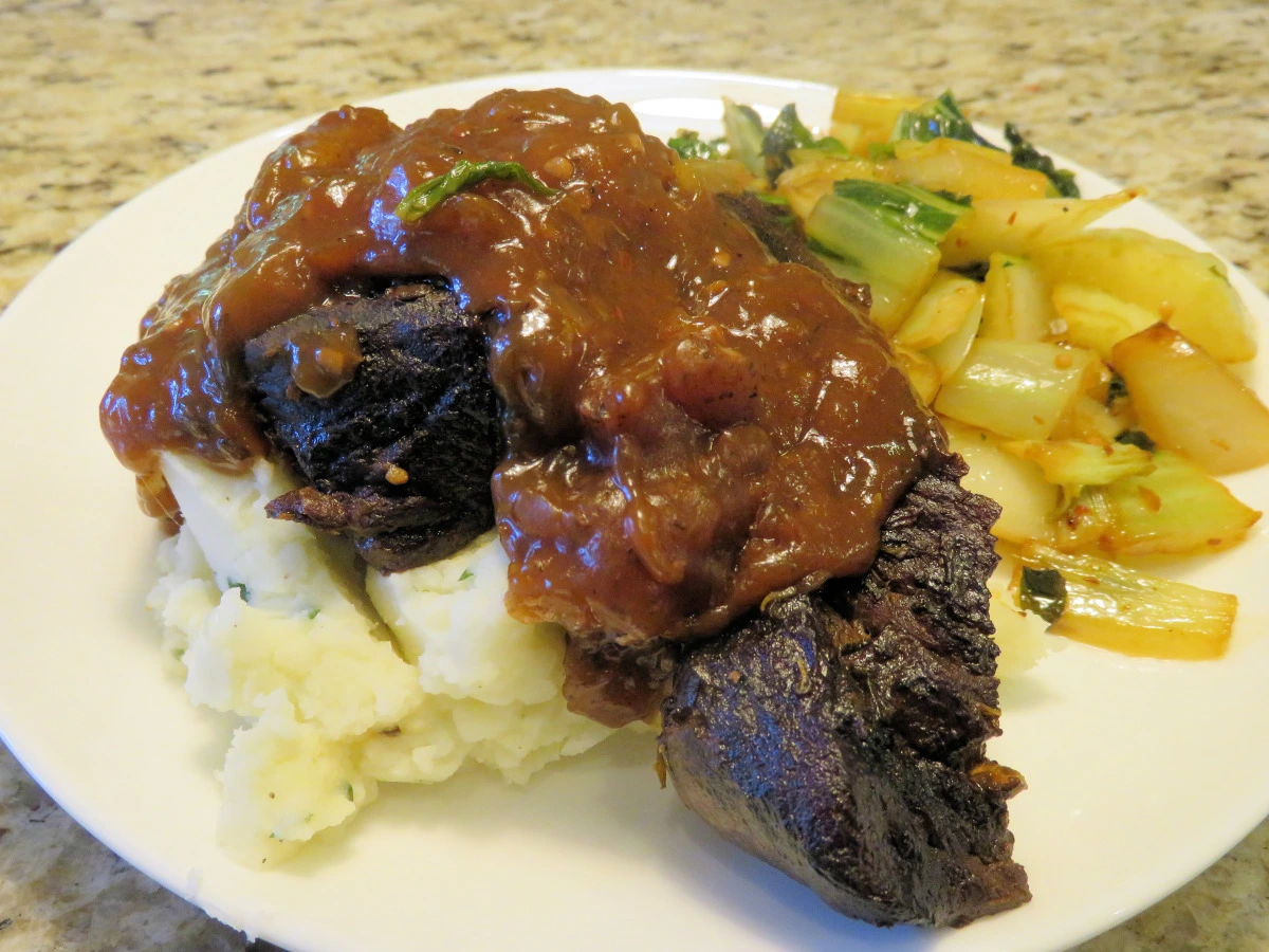 Slow cooker beef short ribs cooking in a crockpot with rich savory gravy