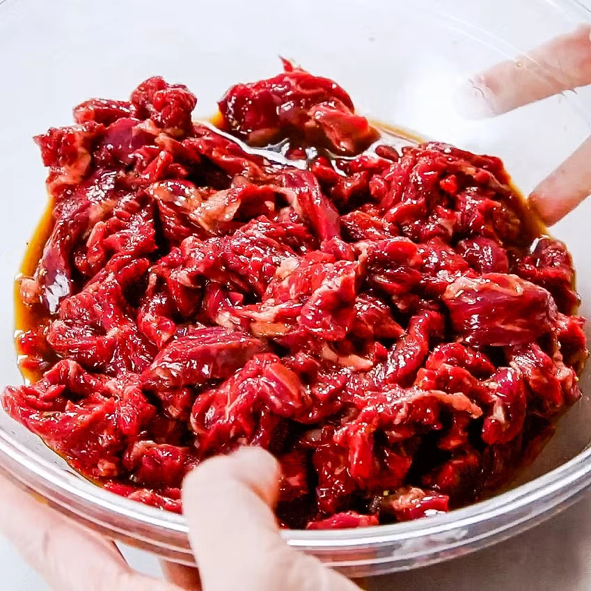 Raw chuck roast sliced into thin strips for slow cooker beef and broccoli recipe.