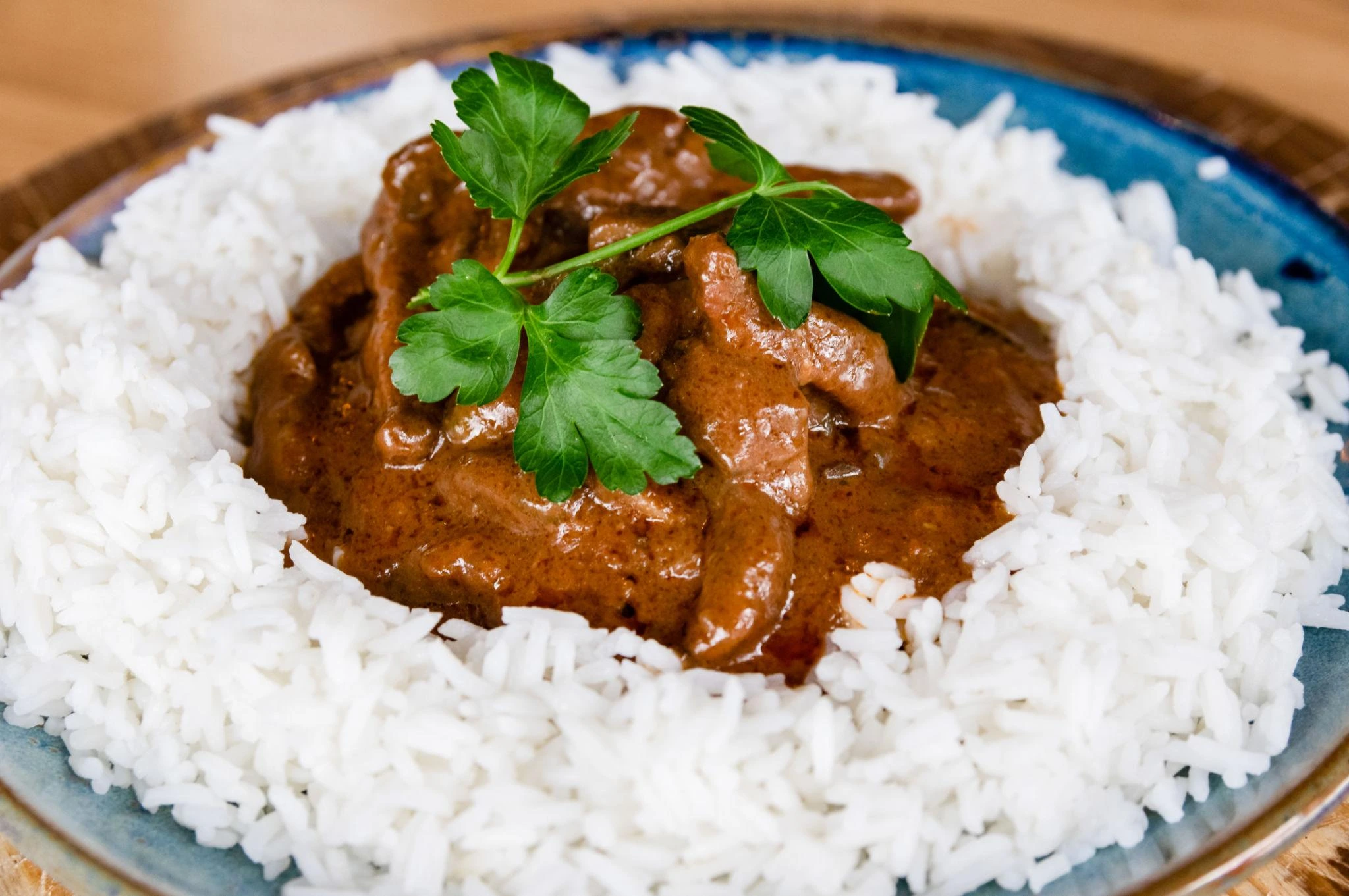 Creamy crockpot beef stroganoff served over white rice in a bowl with tender beef and rich mushroom sauce.