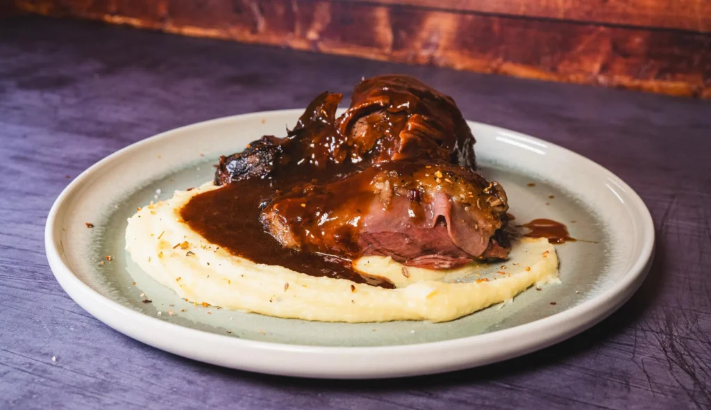 Slow cooker beef shank served with mashed potatoes and rich savory sauce
